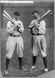 Two batters holding bats, conversing.