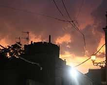 Coria sunset after rain.  Sun is setting behind black silhouette of castle; and it lights heavy dark clouds from below