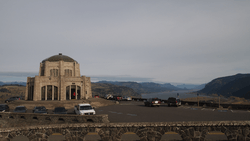 Photograph of a scenic building on a high promontory with an expansive view over a river and canyon