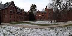 The open courtyard of a four-story manor house-style brick building with trees to the left and right