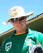 A man in green t-shirt and white cap with the sky in the background