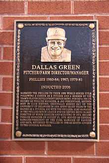 A bronze-and-black plaque mounted on a brick surface and engraved with the face of a smiling man; the primary caption reads "Dallas Green; Pitcher/Farm Director/Manager; Phillies 1960–64, 1967, 1979–81