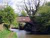 The bridge spans the canal with a footpath on the left and trees on each flank.