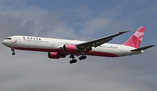  Twin-engine airliner with white and pink colors on approach with landing gear and flaps extended.