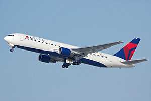 A side/underneath view of a 767-300ER in Delta Air Lines' white, blue and red color during climbout.  The main undercarriage doors are still retracting.