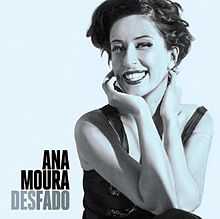 Light-blue toned picture of a smiley woman. She looks at the camera as she has her hands grabbing her neck. She has short black hair, and wears a dress of the same colour. To her right the text "Ana Moura" is written in black capital letters, and below it "Desfado".
