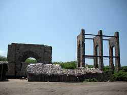 Photograph of the ruined Dhanushkodi Railway Station, surrounded by weeds