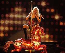 A blonde woman performing on a carousel horse