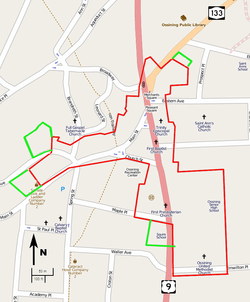 A map of the streets in downtown Ossining, on a gray background with major roads in pink and orange and the locations of some landmarks indicated. The border of the irregularly-shaped historic district is in red. Four small green-bordered areas are adjacent to it.