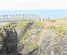 A narrow metal bridge crosses a steep gorge