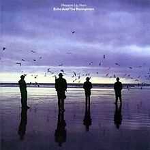 An album cover showing four men in silhouette standing on a wet beach. There are dark clouds in the sky and the sun is low on the horizon. The album's name and the band's name is in white letters in the top centre of the album cover.