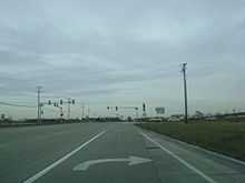 Approaching intersection with IL 60. Road is 2 lanes in each direction, concrete lanes. Traffic signal lies ahead from viewpoint of right turn lane.