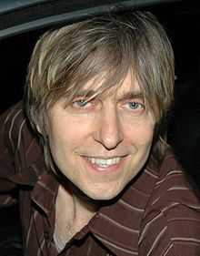 Head shot of a man wearing a brown-striped shirt