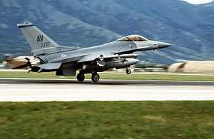 A fighter jet with AV marked on its tail takes off from a mountain runway.