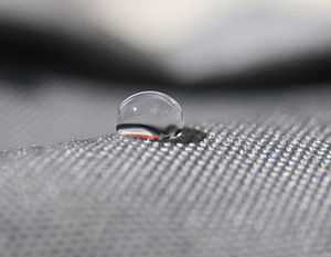 side view of a drop of water on a gray cloth. Looks like about a 120 degree angle.