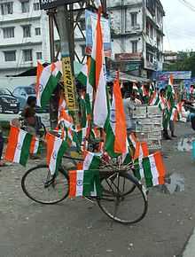 Several flags mounted on a bicycle parked on a road.