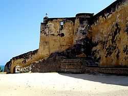 A fortified, but badly-faded yellow-coloured wall looks off into distant sea to the left.