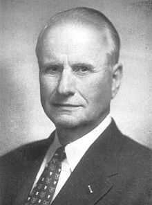 Black-and-white photo of gray-haired man in front profile wearing suit.