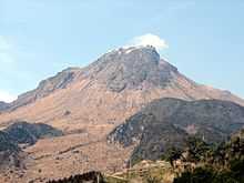 Volcano with smoking rocky top and lower parts without vegetation.
