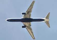 Underside view of a jet in-flight. Each wing of the two wings have an engine. Towards the left are the horizontal stabilizers.