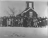 Black and white photograph of a wooden church building with a crowd of people in front of it