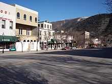 A set of attached two and three-story commercial buildings seen from across a street with a mountain behind them