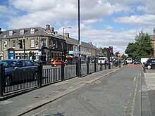 A 19th-century public house building and shops behind a road and pavement