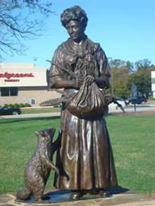 Bronze statue of Colonial American woman with a basket of rosemary and a raccoon
