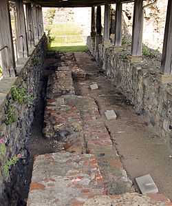 Trench with three grave markers covered by a wooden roof.