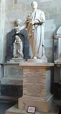 White stone statue of a man in a toga, in a stone building