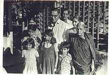 A black and white photo of H. R. Janardhana Iyengar with his wife, daughter and grandchildren in front of his house in the late 1970s