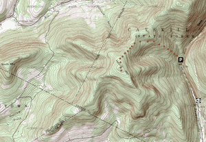 A topographic map with green and white background behind brown contour lines with a semicircle of brown dots in the middle beginning at a black and white "P" sign on the right. Below it is a sign with the number 42.