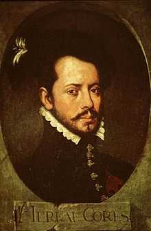 Old painting of a bearded young man facing slightly to the right. He is wearing a dark jacket with a high collar topped by a white ruff, with ornate buttons down the front. The painting is dark and set in an oval with the letters "HERNAN CORTES" in a rectangle underneath.