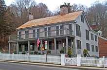 The house viewed from its left. In this image the roof has wooden shingles