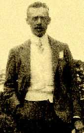 Photo of Burnham's brother Mather Howard Burnham.  Howard is wearing a suit and tie and standing with his right hand in his pocket.