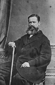 b&w seated portrait photo of a bearded man