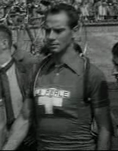 Black-and-white image of a man in a shirt with a cross.