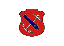 An insiginia in the form of a red shield. On the shield are a white anchor crossed by a blue cannon barrel.