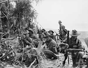 Soldiers resting on a river bank on the edge of the jungle