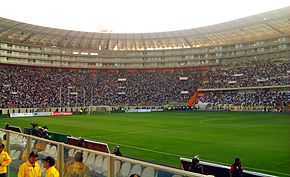 Photograph of a modern football stadium's interior; the stands are full of spectators