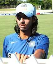 A man in blue t-shirt and sky-blue cap with the sky in the background