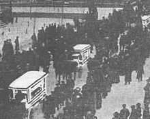 Crowded procession with three white caskets visible