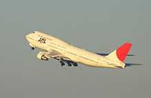 A Boeing 747–300 aircraft in mid air during take-off, with grey sky in the background