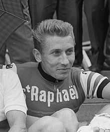 A man wearing a cycling jersey while smiling.