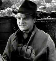 Head and shoulders shot of Cagney, wearing black fedora and smiling slightly; scenery in the background.