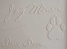 Jay Miner's signature from the top cover of a Commodore Amiga 1000 computer, along with his dog Mitchy's pawprint.