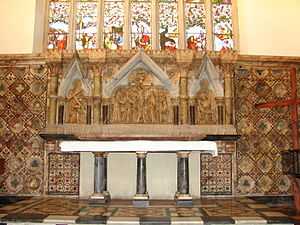 A marble reredos beneath a stained glass window, with three scenes from the Crucifixion; a granite altar with six pillars