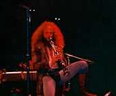 Jethro Tull leader Ian Anderson, wearing a codpiece and tights, stands on one leg as he plays a soprano saxophone