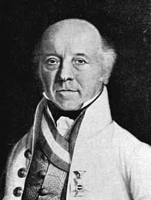 Black and white print of a middle-aged bald man in a white, high-collared coat. He has a tuft of hair near each ear and a military award on the breast of his coat.