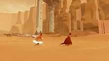 A red-robed figure runs through the sand in front of some stone ruins, accompanies by another figure. The trailing figure's robe and scarf are glowing.